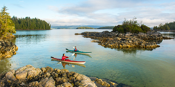 Two kayakers paddle calm waters.