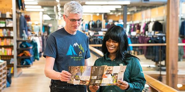 A Parks Canada employee provides information to a man in a MEC store.