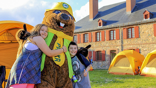 Parka posing for a photo with young visitors at Fortress of Louisbourg National Historic Site.