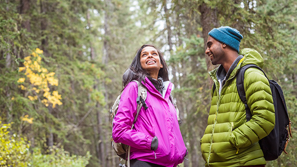 Un couple en randonnée dans la forêt sur le sentier du Lac-Minnewanka au parc national Banff.