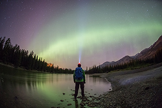 A man standing on a rock looking at the dark sky in Jasper National Park.