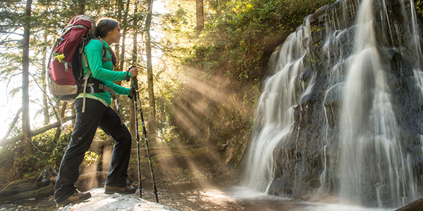 A female hiker marvels at the picturesque waterfall at Bonilla Creek in Pacific Rim National Park Reserve.