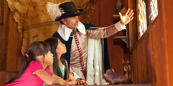 A heritage interpreter in period costume speaks with young visitors at Port-Royal National Historic Site.